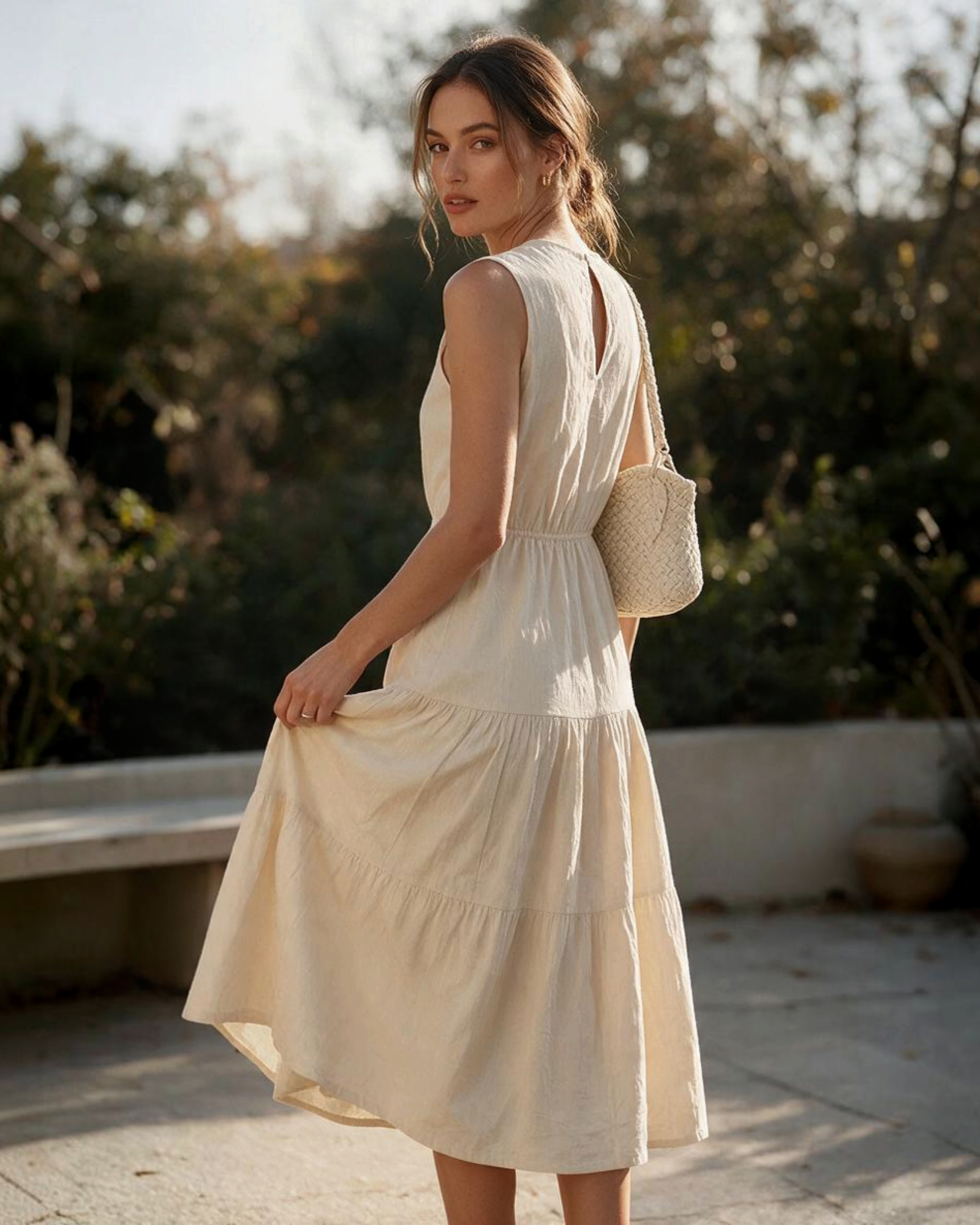 Mujer luciendo un vestido midi beige de Yanet Collective con falda escalonada y detalle en la cintura al aire libre
