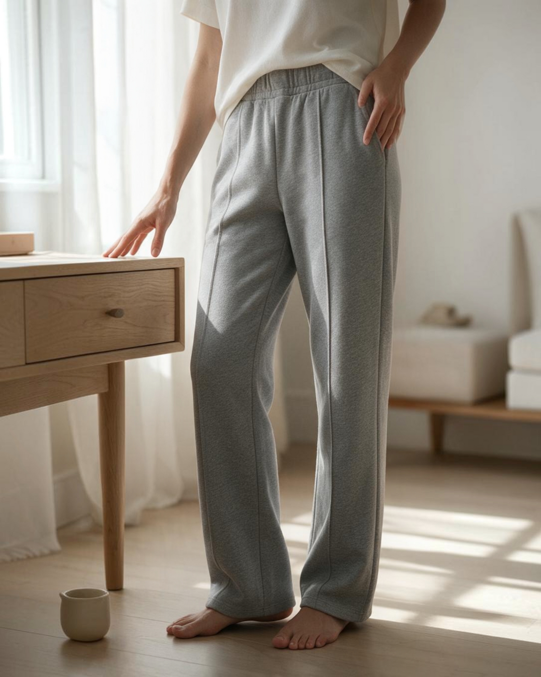 Pantalones de vestir elásticos grises Yanet Collective con frente plisado y corte relajado en un entorno luminoso